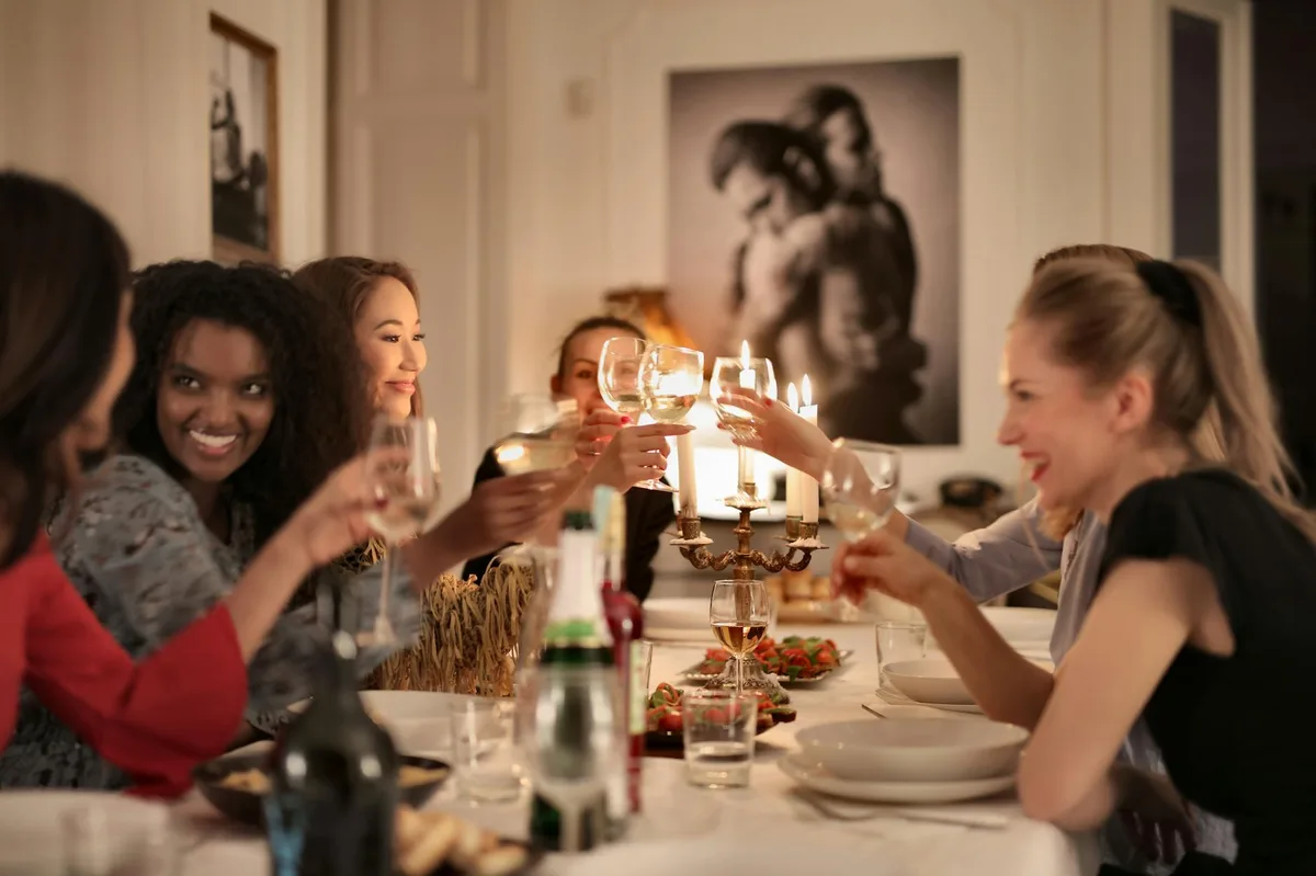 A group of friends enjoying a dinner party, toasting with wine glasses around a candlelit table.